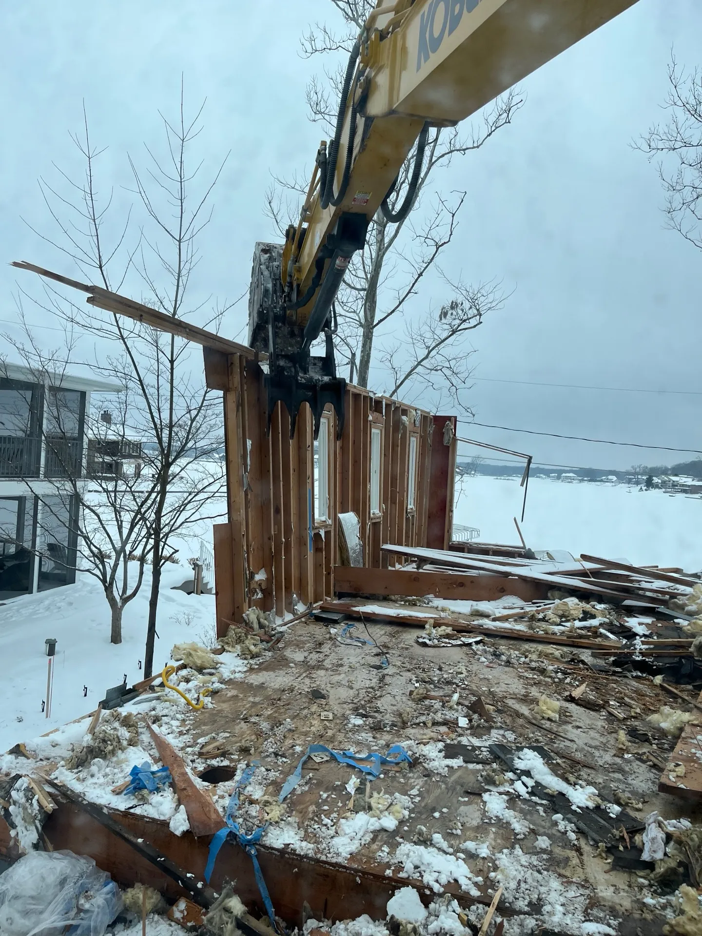 Yellow excavator setting a fresh foundation in the snow at a Kalamazoo home