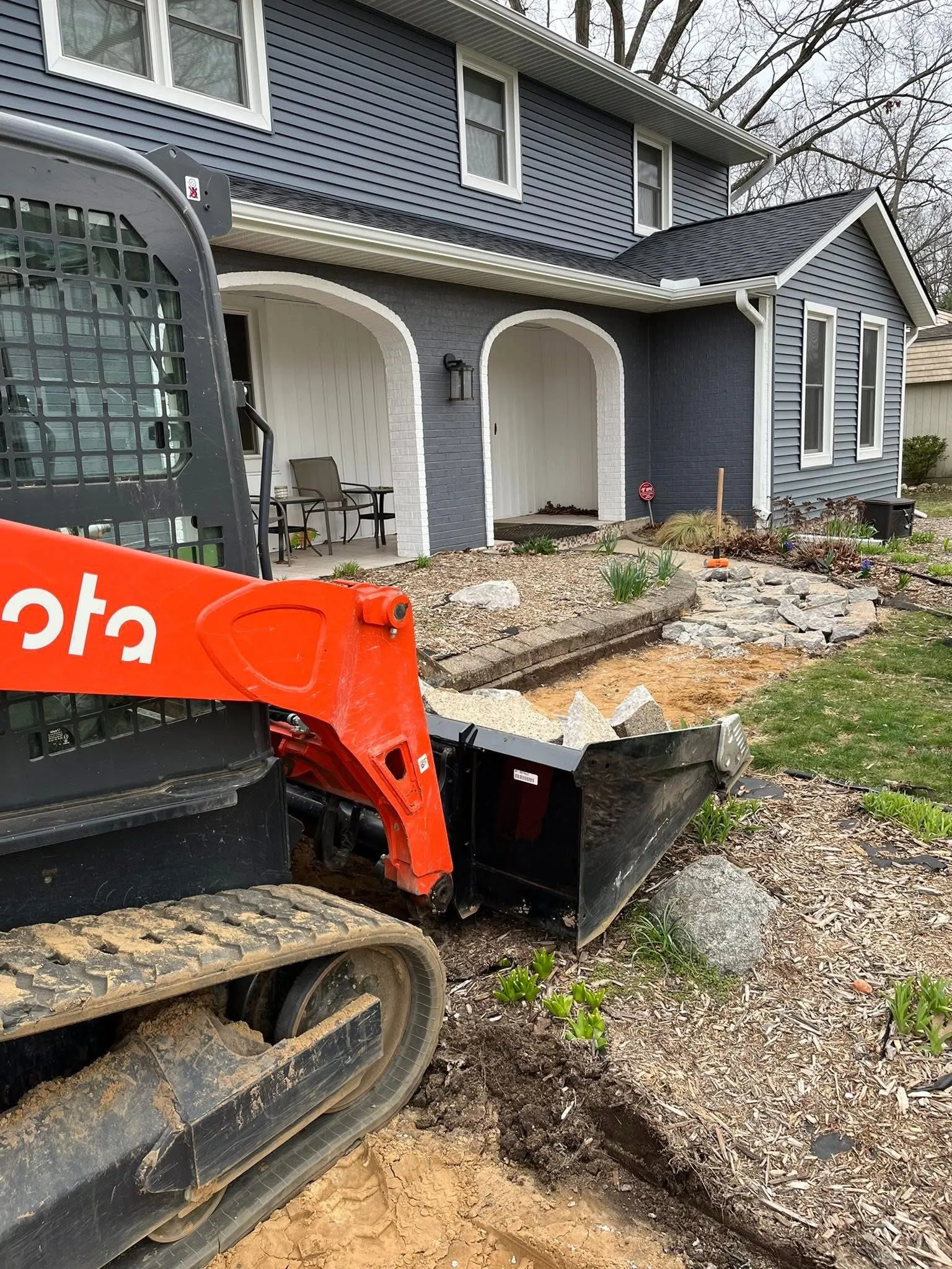 Compact track loader regrading and setting stone in a Kalamazoo front yard